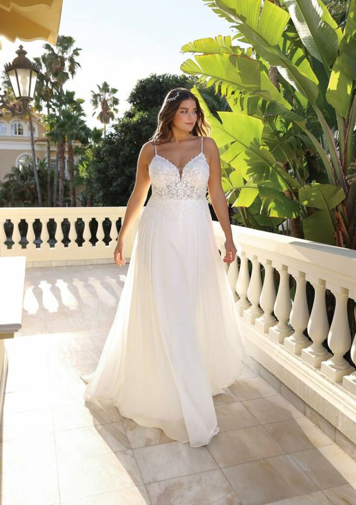 Brautkleid mit zarten Trägern, Spitzenoberteil und glattem Rock auf einer Terrasse